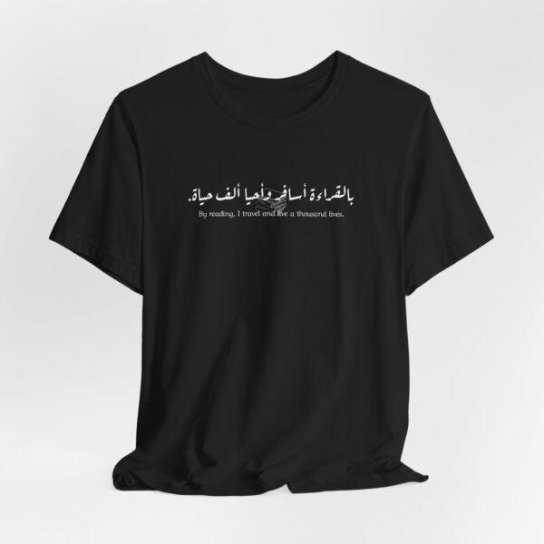 Book Lover Arabic t-shirt with Arabic-English quote 'بالقراءة أسافر وأحيا ألف حياة' ('By reading, I travel and live a thousand lives') and stacked books illustration.