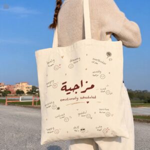 Woman carrying Arabic bag مزاجية Emotionally Scheduled Arabic aesthetic canvas tote bag outdoors