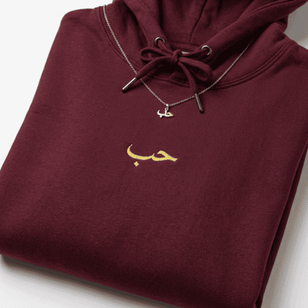 Close-up of gold حب Arabic embroidery on maroon hoodie